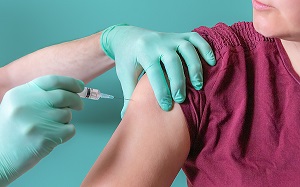 Nurse holding syringe gives injection to female patient. Woman vaccinating in vaccine center of hospital. Vaccination in shoulder. Safety from coronavirus concept